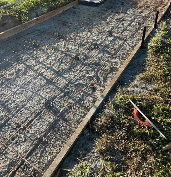 A Concrete Driveway is Being Built Next to a Grassy Area — Adzcom Civils in Portsmith, QLD