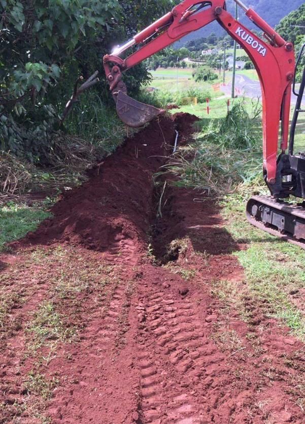 A Red Kubota Excavator Digging a Hole in the Ground — Adzcom Civils in Portsmith, QLD