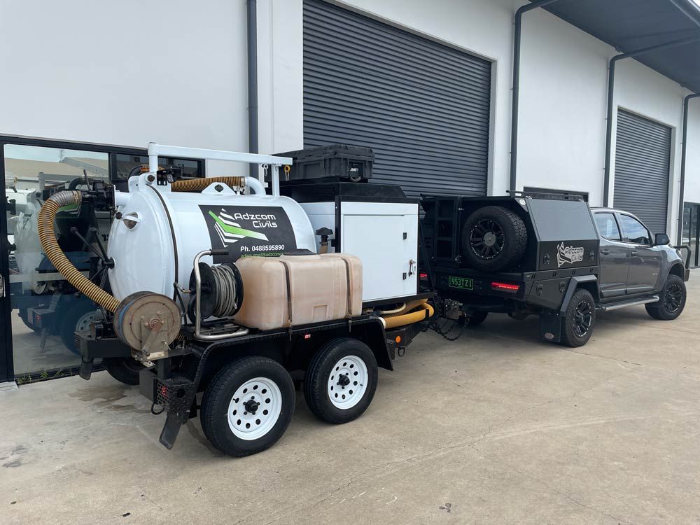 A Vacuum Truck With a Trailer Attached to It — Adzcom Civils in Portsmith, QLD