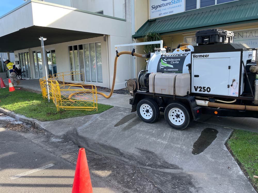A Vacuum Truck is Parked in Front of a Building — Adzcom Civils in Portsmith, QLD