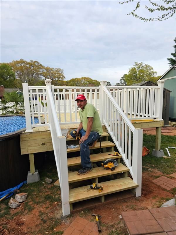 A man is kneeling on a set of wooden stairs next to a pool.
