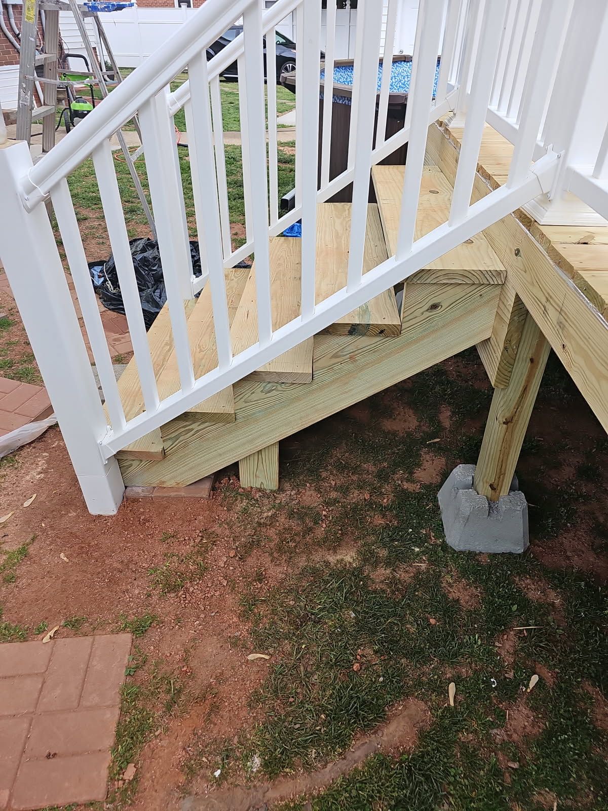 A wooden deck with stairs and a white railing is being built.