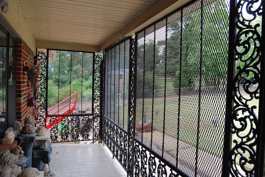 a screened in porch with a wrought iron railing and a view of the backyard .