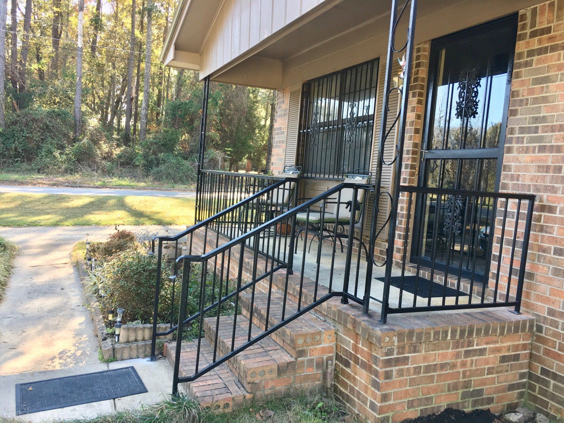 a brick house with a wrought iron railing on the porch .