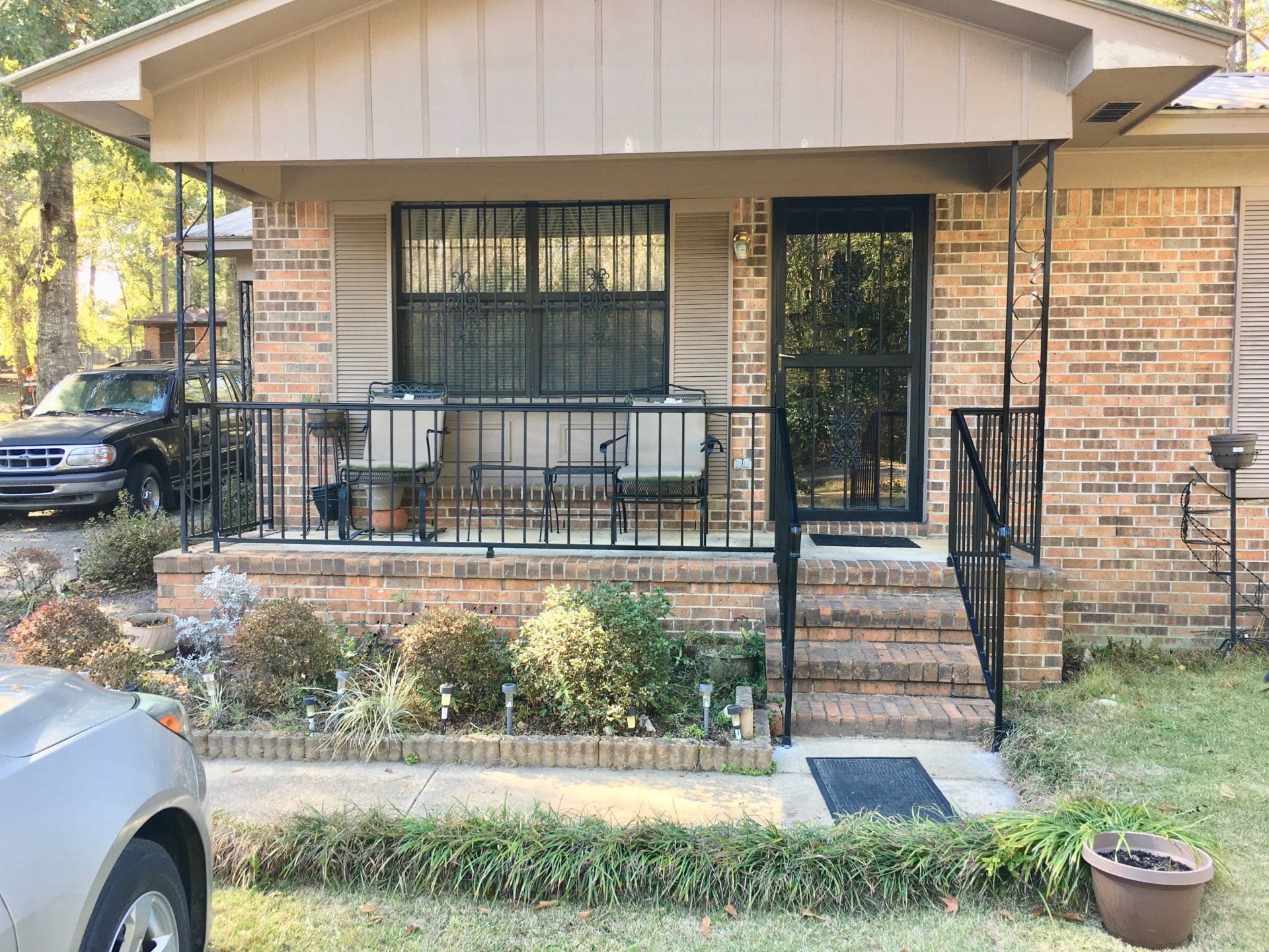 a brick house with a porch and a car parked in front of it .