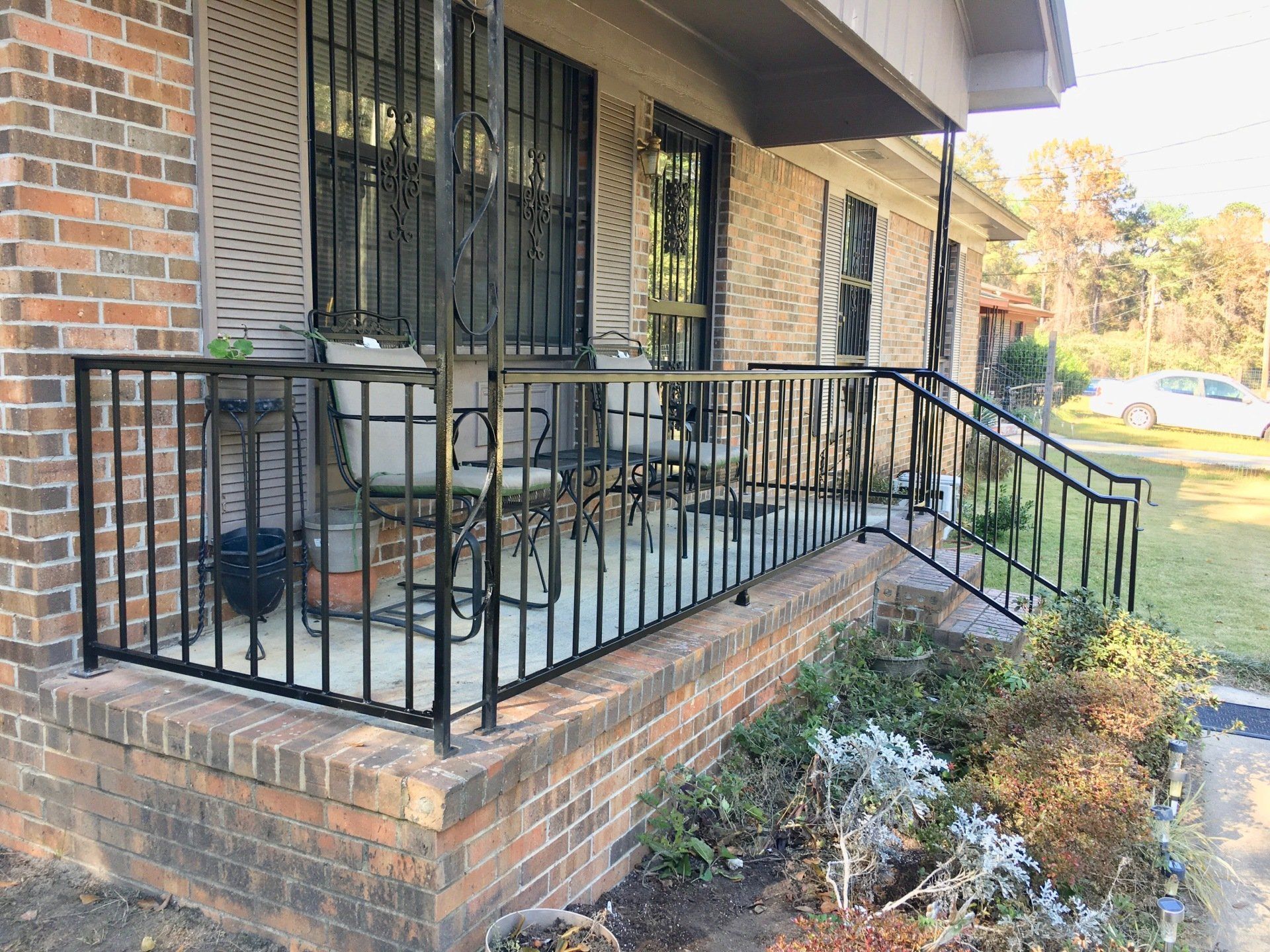 a brick house with a porch and a wrought iron railing .