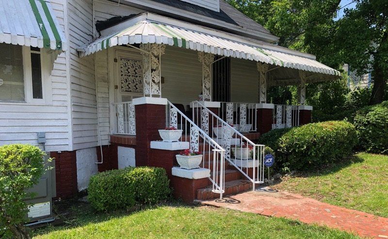 a white house with a green and white awning on the porch .