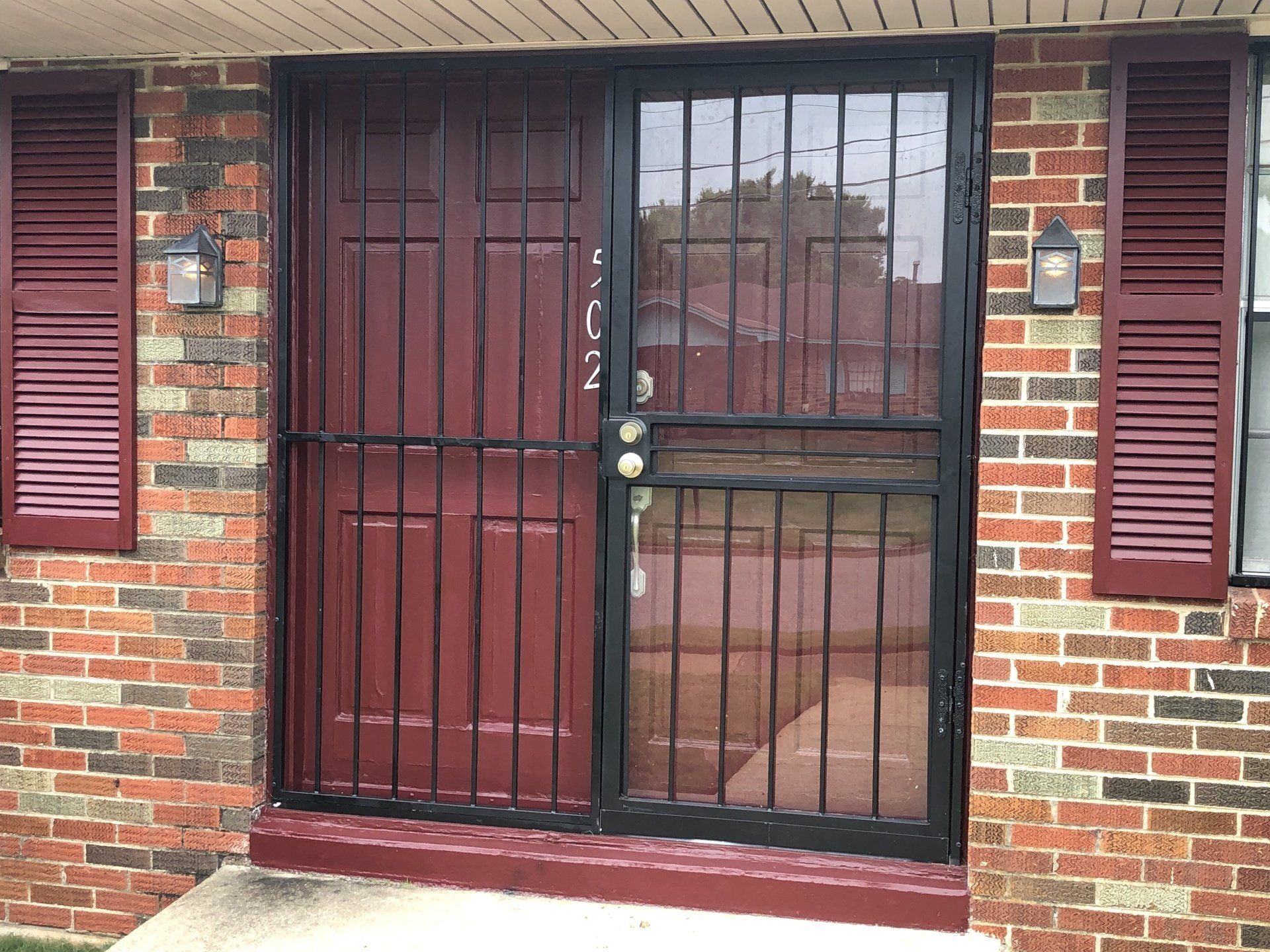 a brick building with a red door and shutters