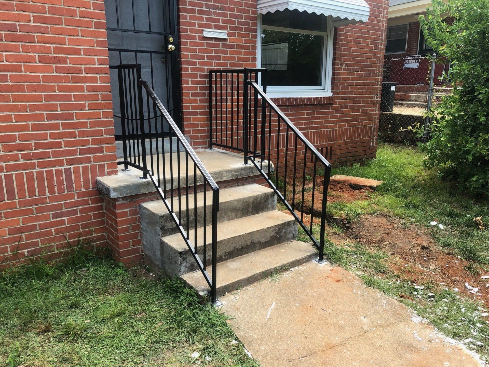 a brick house with stairs and a wrought iron railing .