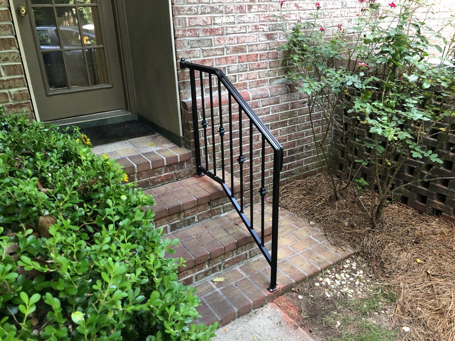 there is a wrought iron railing on the steps of a brick house .