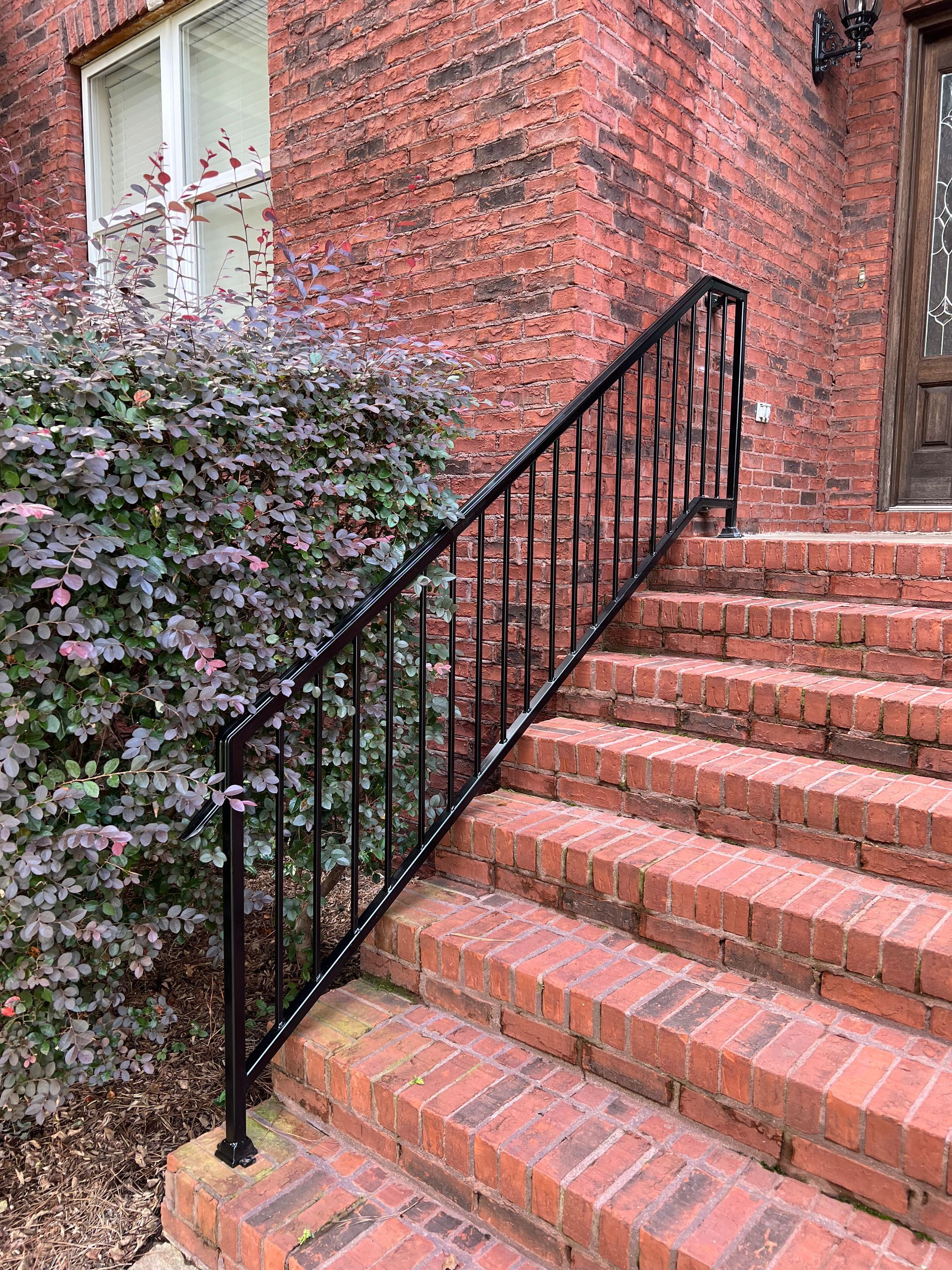 a set of stairs leading up to a brick building with a black railing .