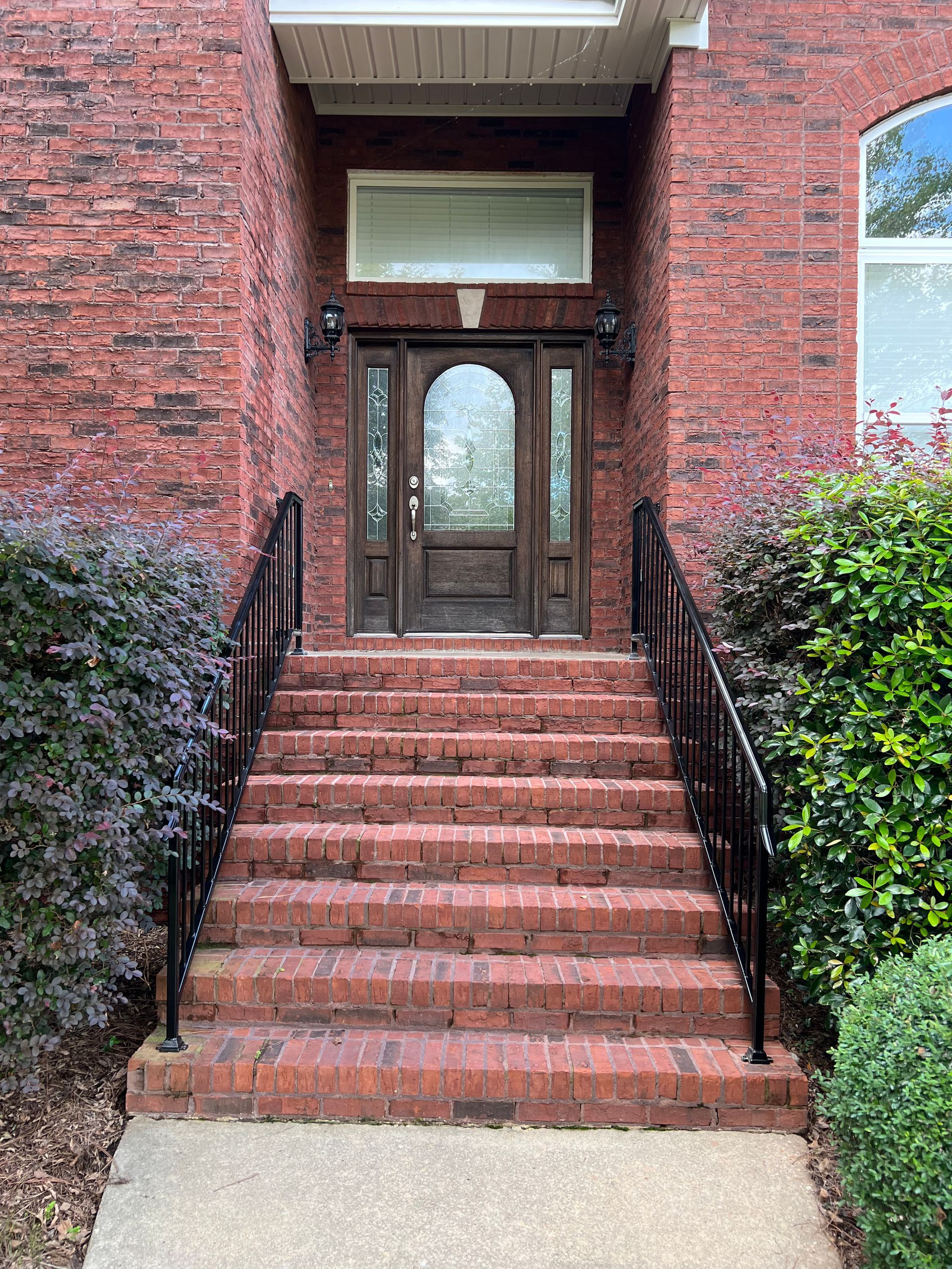 the front door of a brick house with stairs leading up to it .