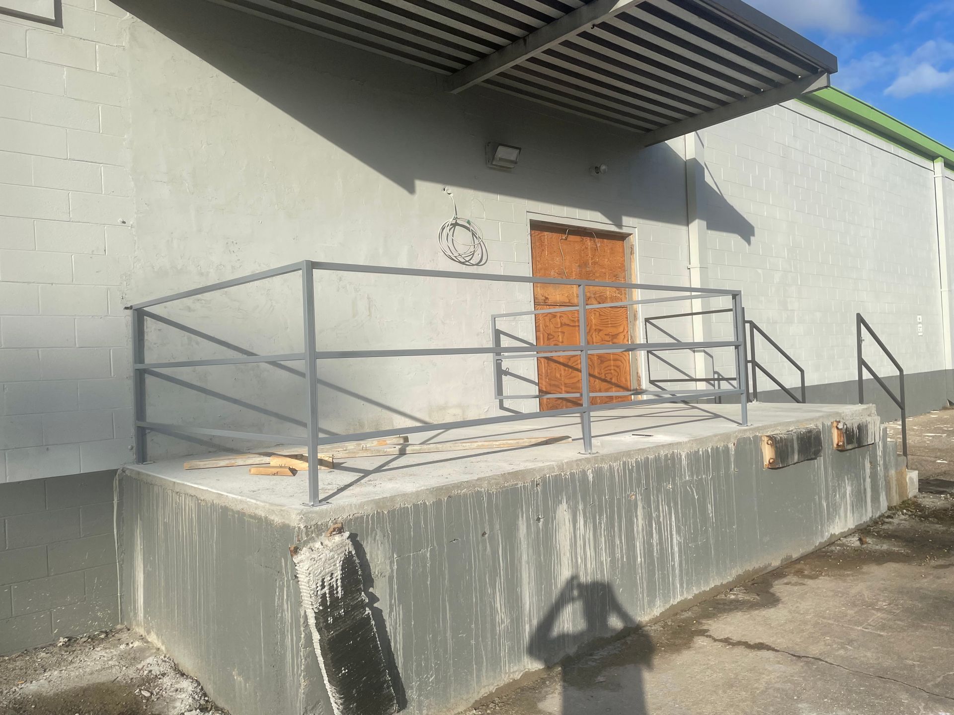 a white building with a metal railing and a wooden door .