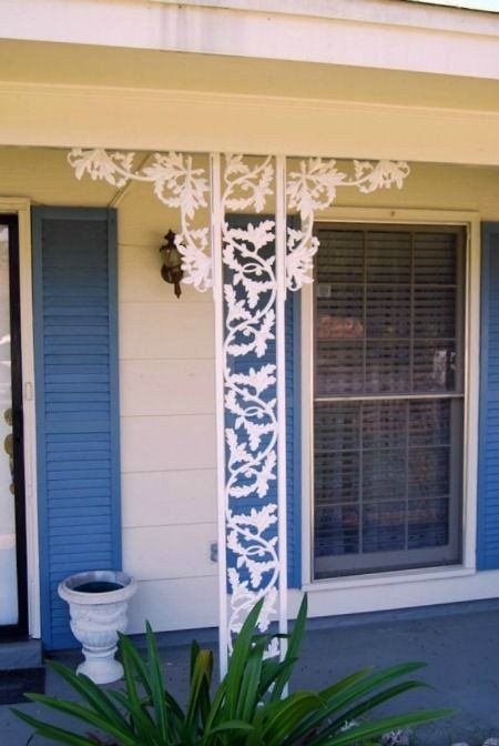 a white porch with blue shutters and a white potted plant