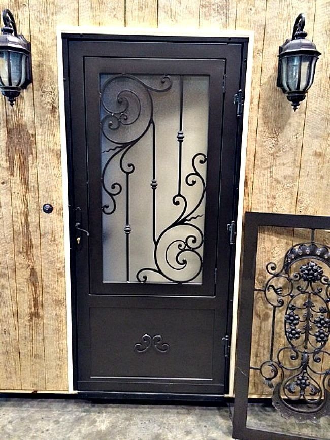 a wrought iron door is sitting in front of a wooden wall .