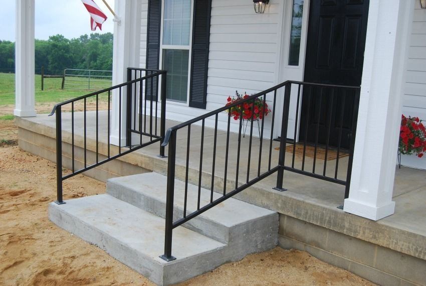 a white house with a black railing on the porch .