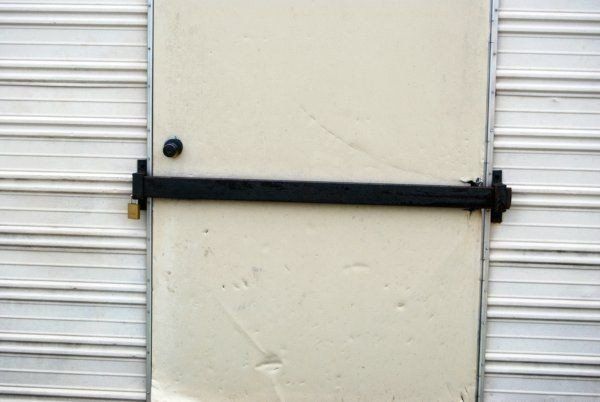 a white door is locked with a black bar .