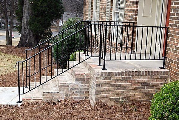 a brick house with a wrought iron railing on the porch .