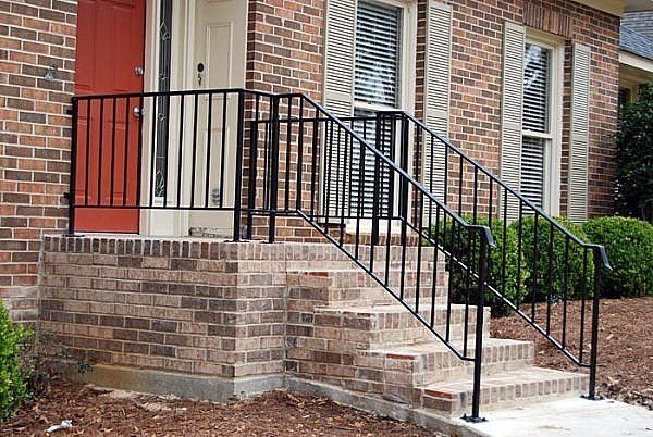 a brick house with stairs and a wrought iron railing .