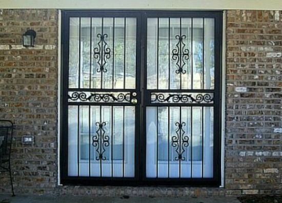 a wrought iron door with a brick wall behind it
