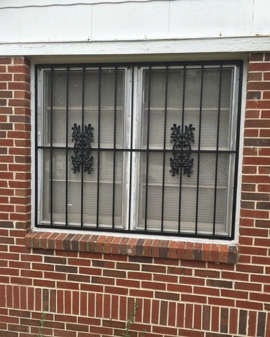 a brick wall with a window with a metal grill on it .