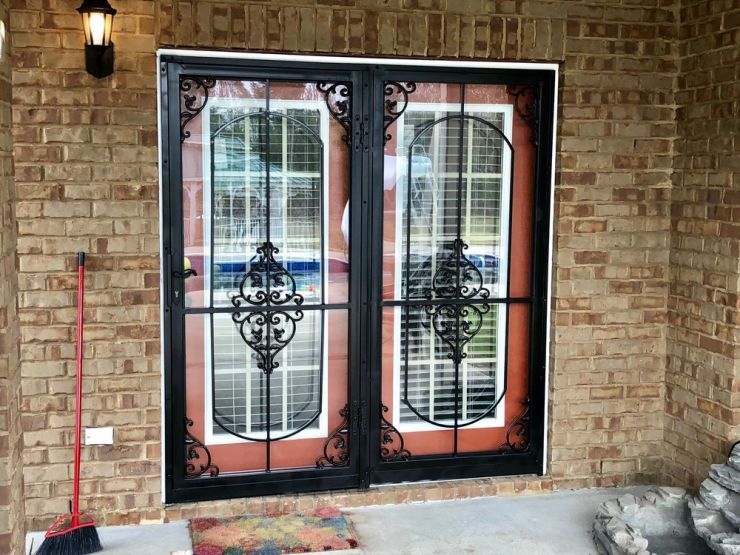 a door with a wrought iron gate is on a brick wall .
