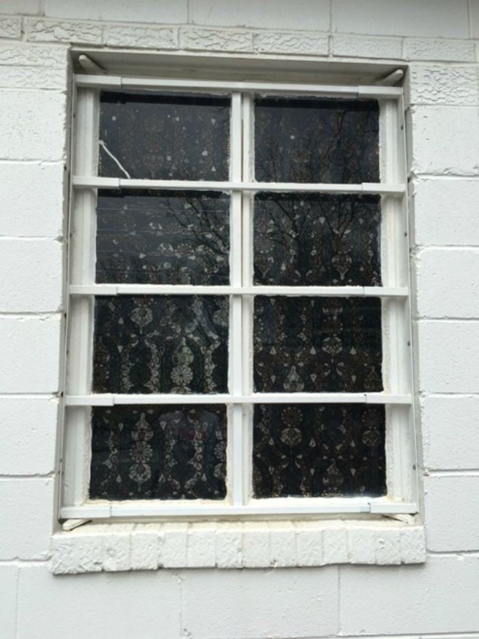 a window on a white brick wall with a black glass