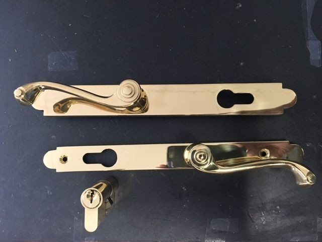 two brass door handles with keys on a black surface