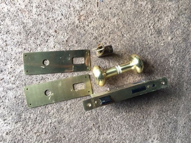 a set of brass door handles and plates on a concrete surface .
