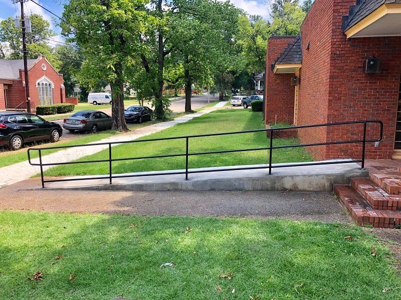 a ramp with a railing is leading to a brick building .