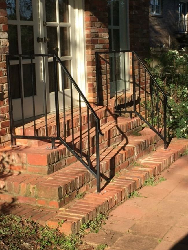a brick house with a metal railing on the steps