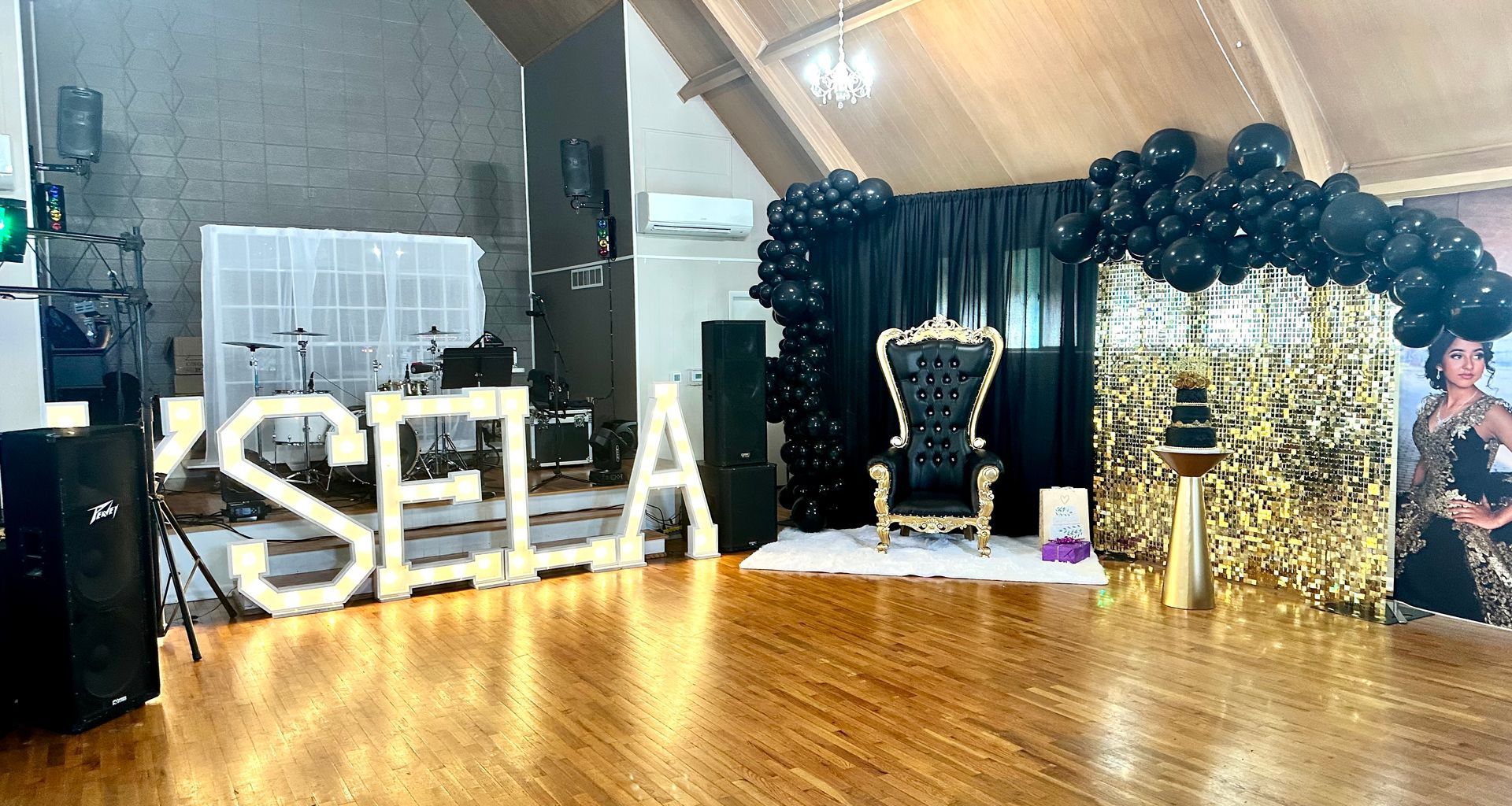 Party venue with a throne, balloons, and illuminated name 