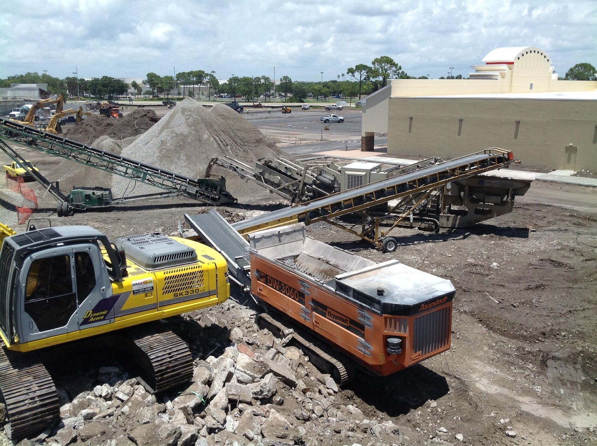 A yellow and black excavator is demolishing a building.