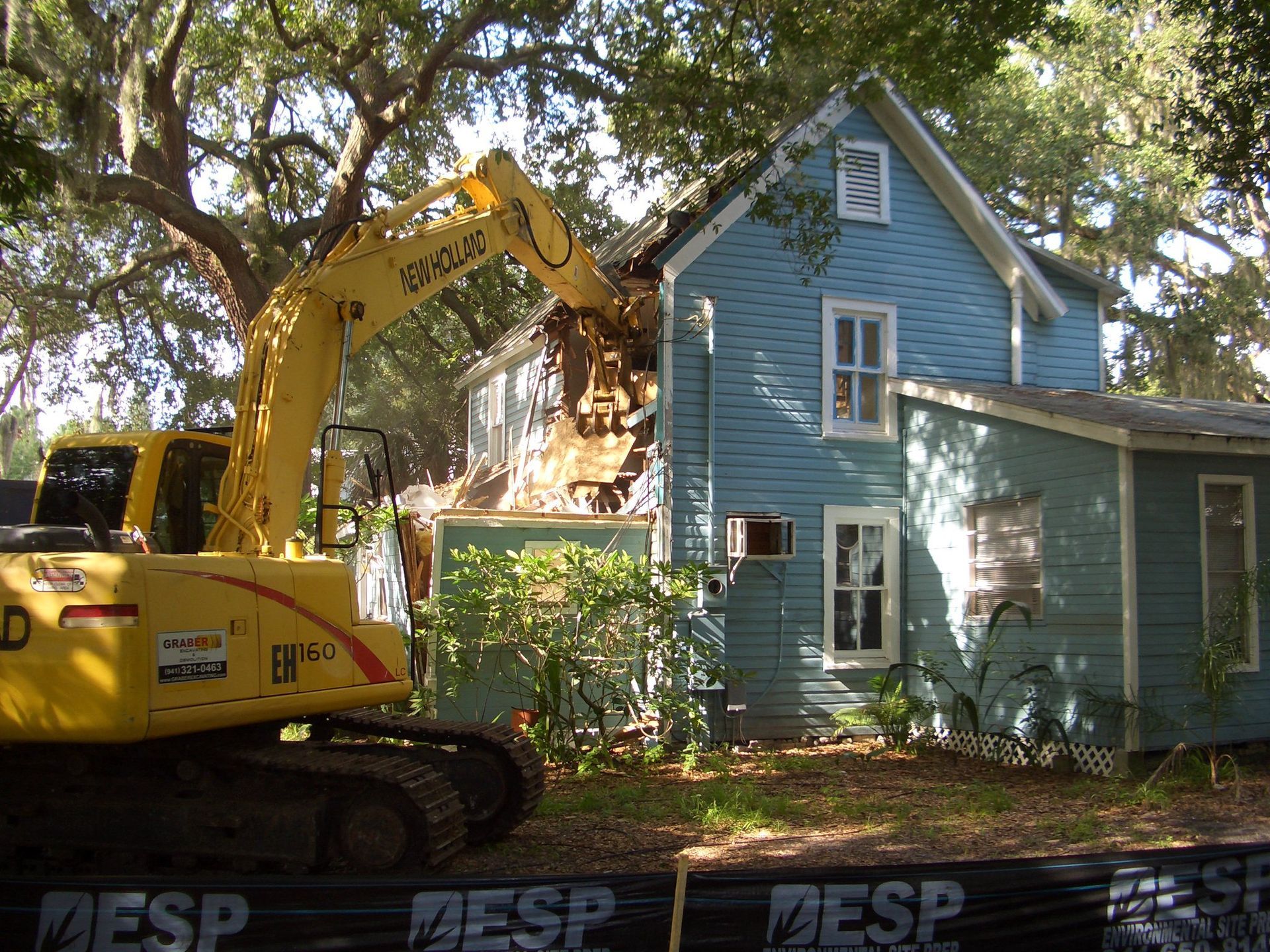 A large pile of wood is in front of a brick house.