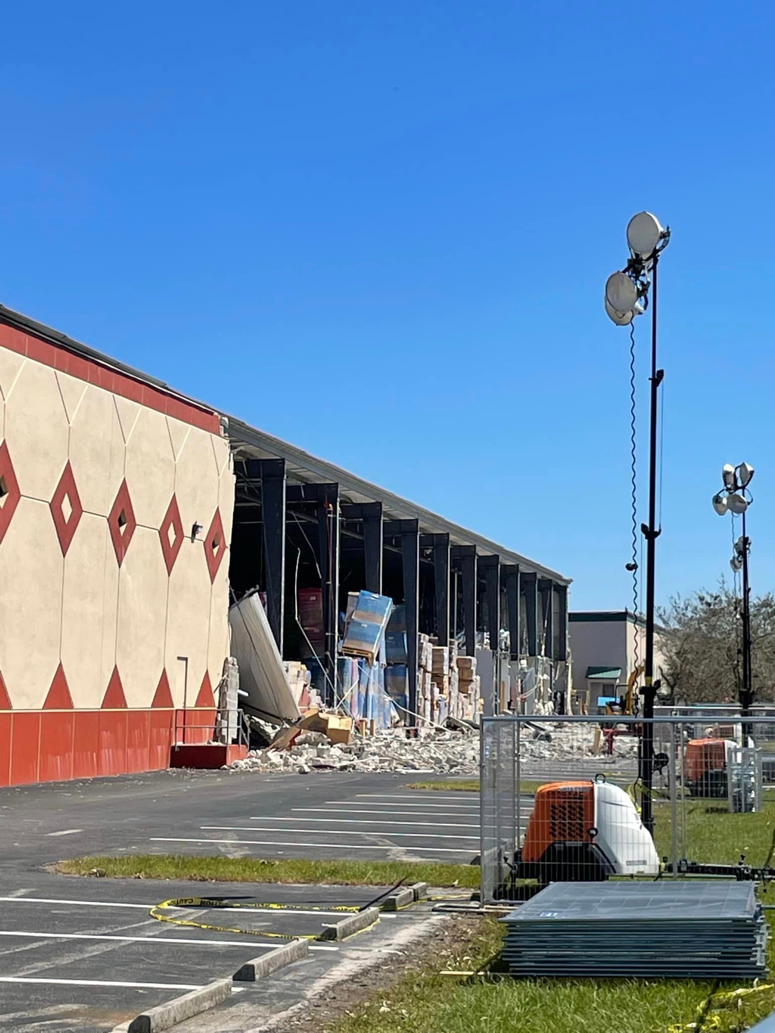 A large white excavator is demolishing a building.