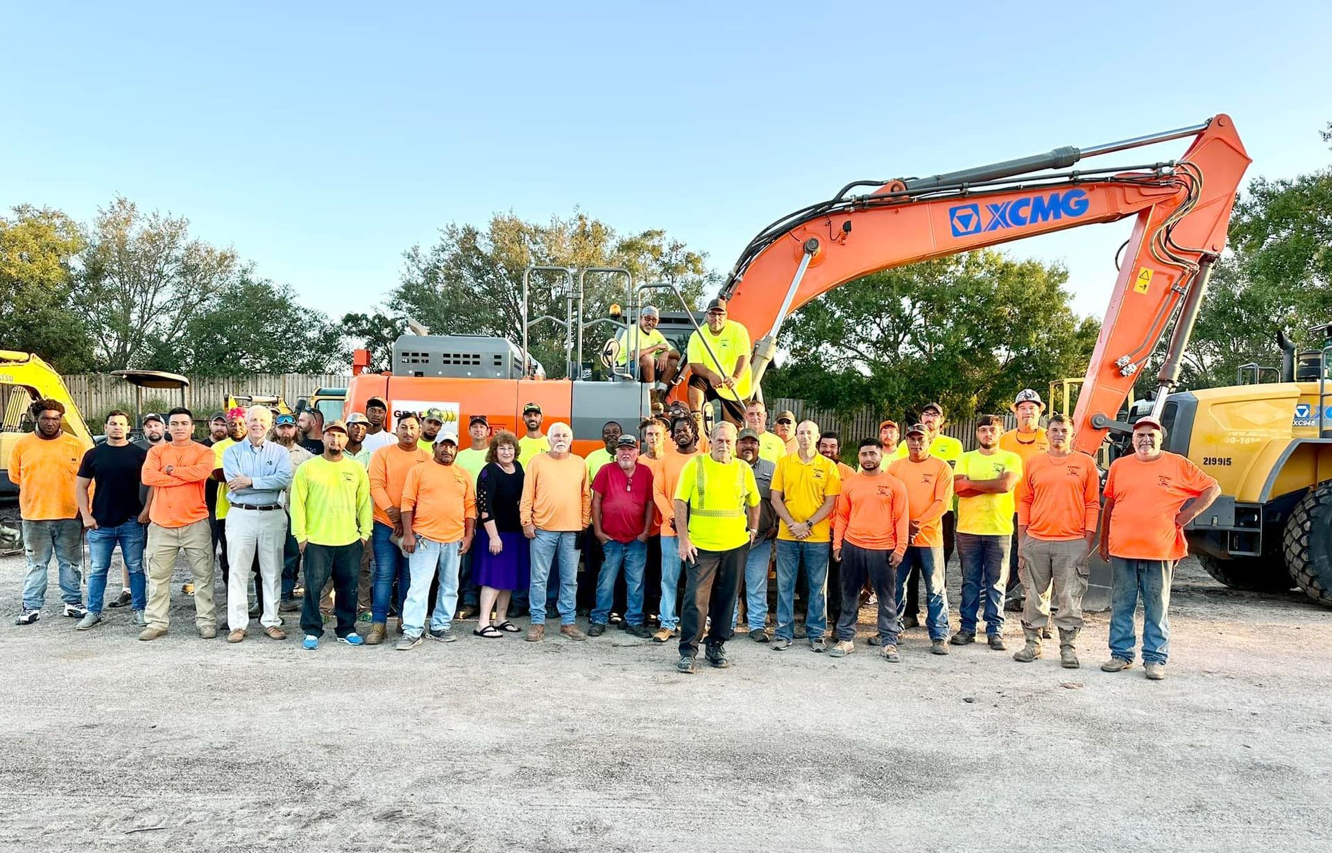 A yellow excavator with a large bucket is sitting in a dirt field.