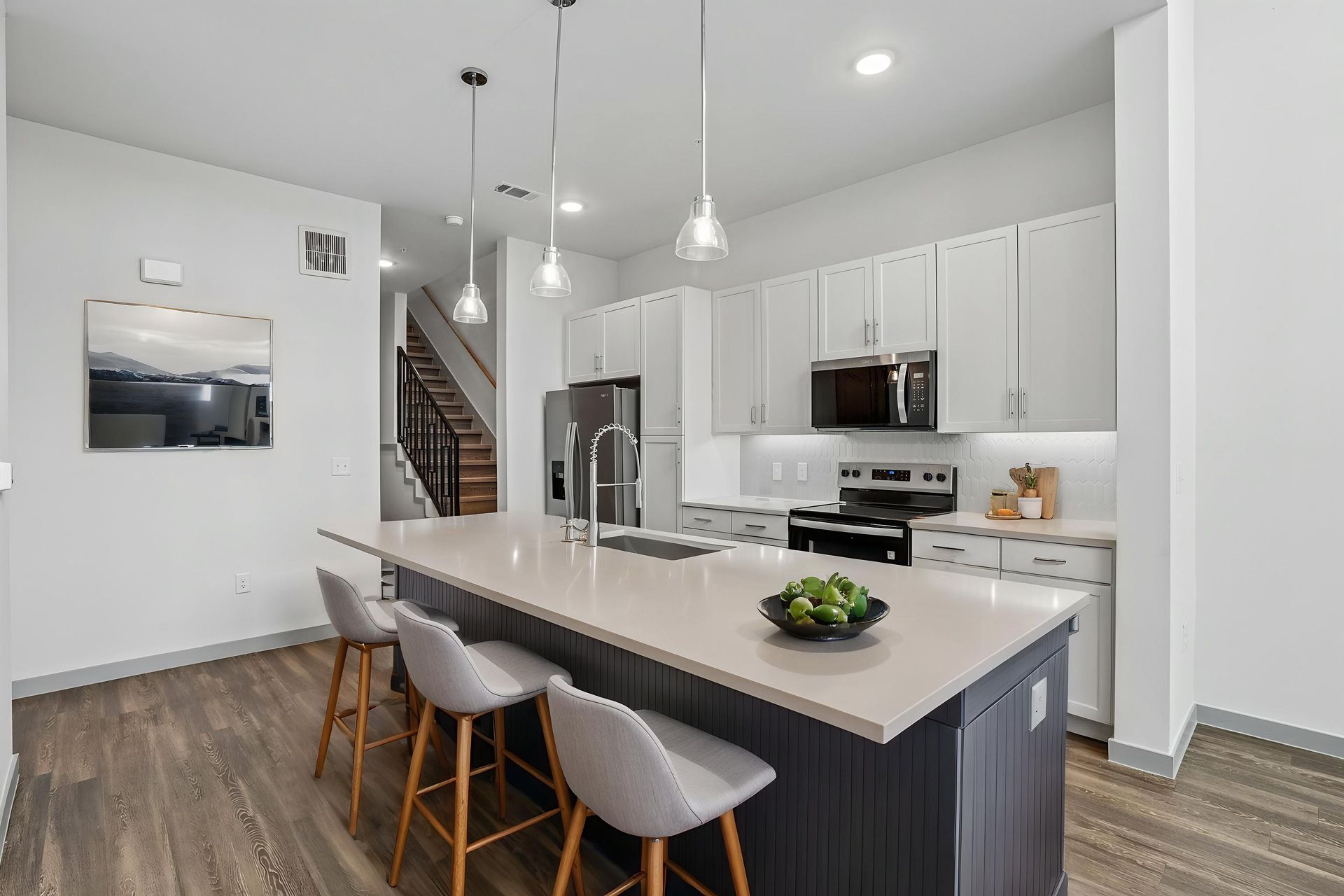 Bright modern kitchen with white cabinets, island, wood floors, and large windows overlooking open space