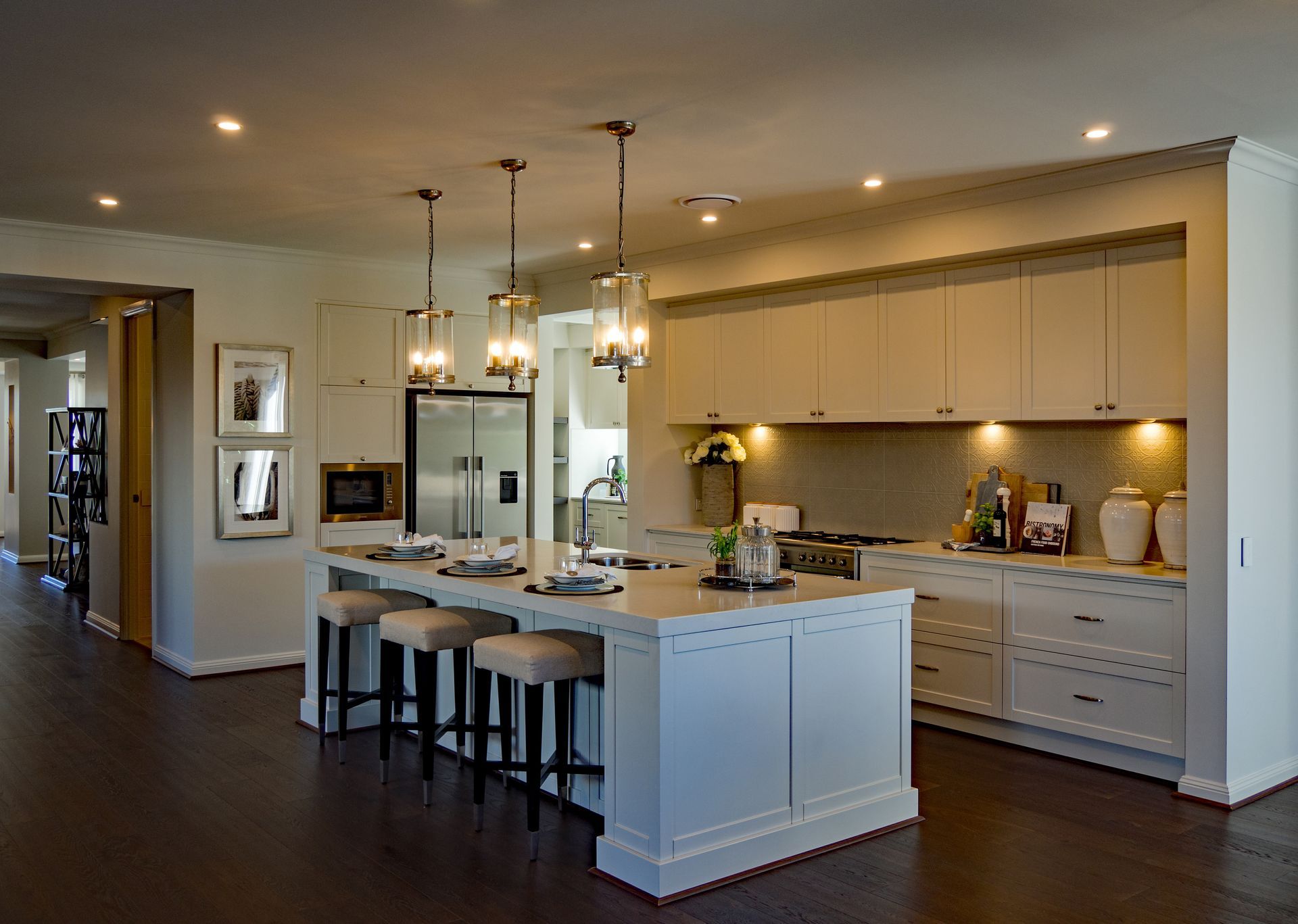 Modern kitchen with island, pendant lights, bar stools, and white cabinetry in an open floor plan