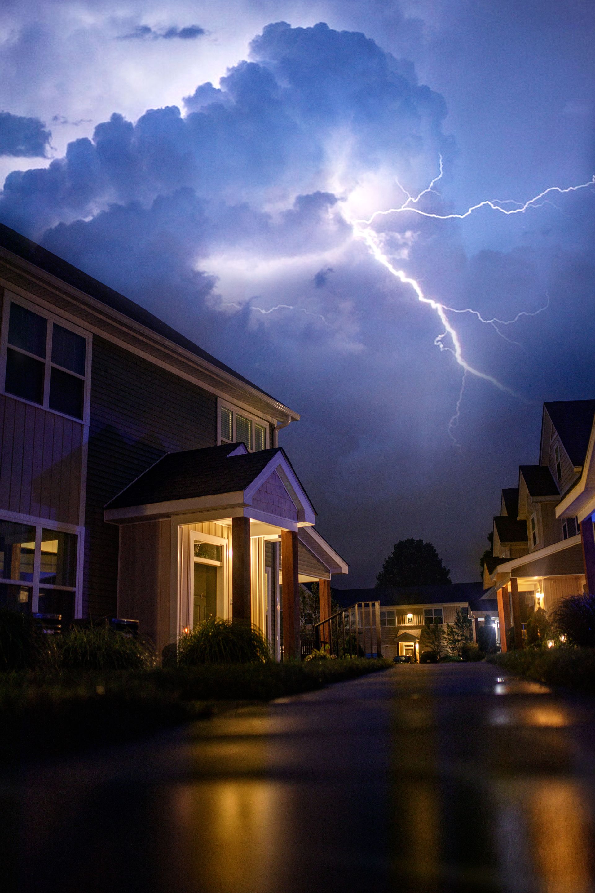 Small house beneath a storm cloud with lightning on a blue background Small house beneath a storm cloud with lightning on a blue background