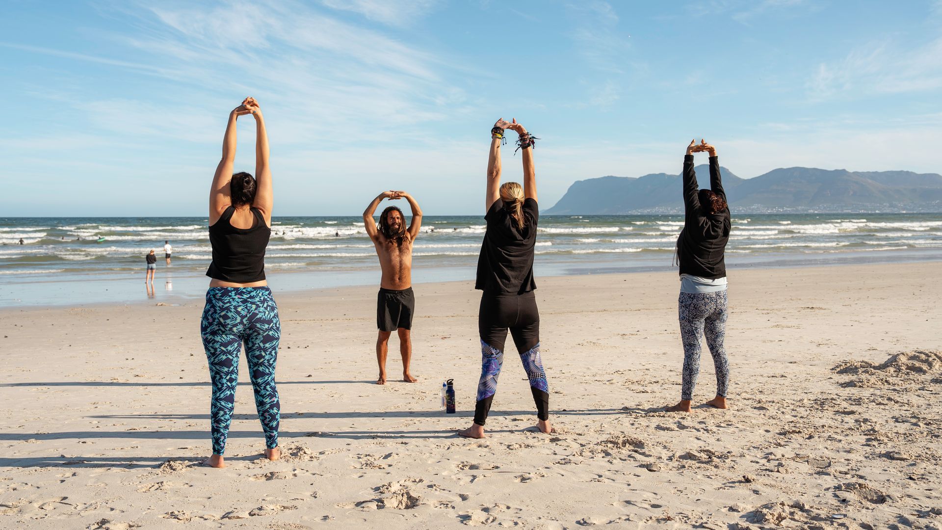 A group of people are doing yoga on the beach.