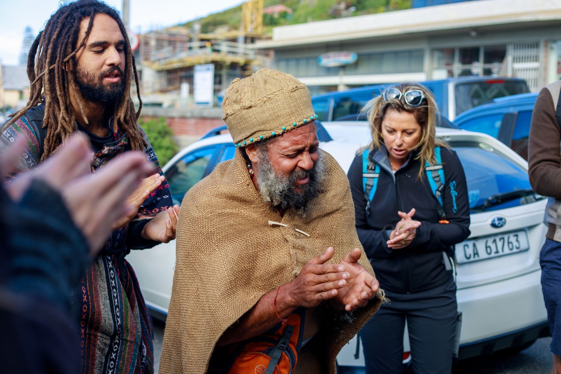 A man with dreadlocks and a beard is standing in front of a group of people.