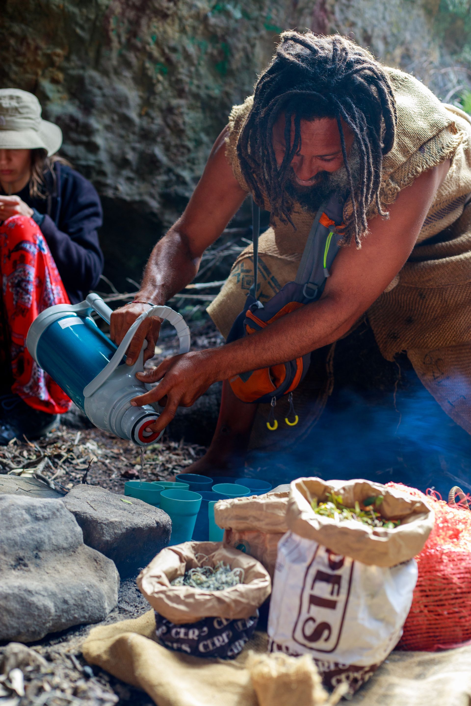 A man is cooking in a cave with a bag that says ' his ' on it.