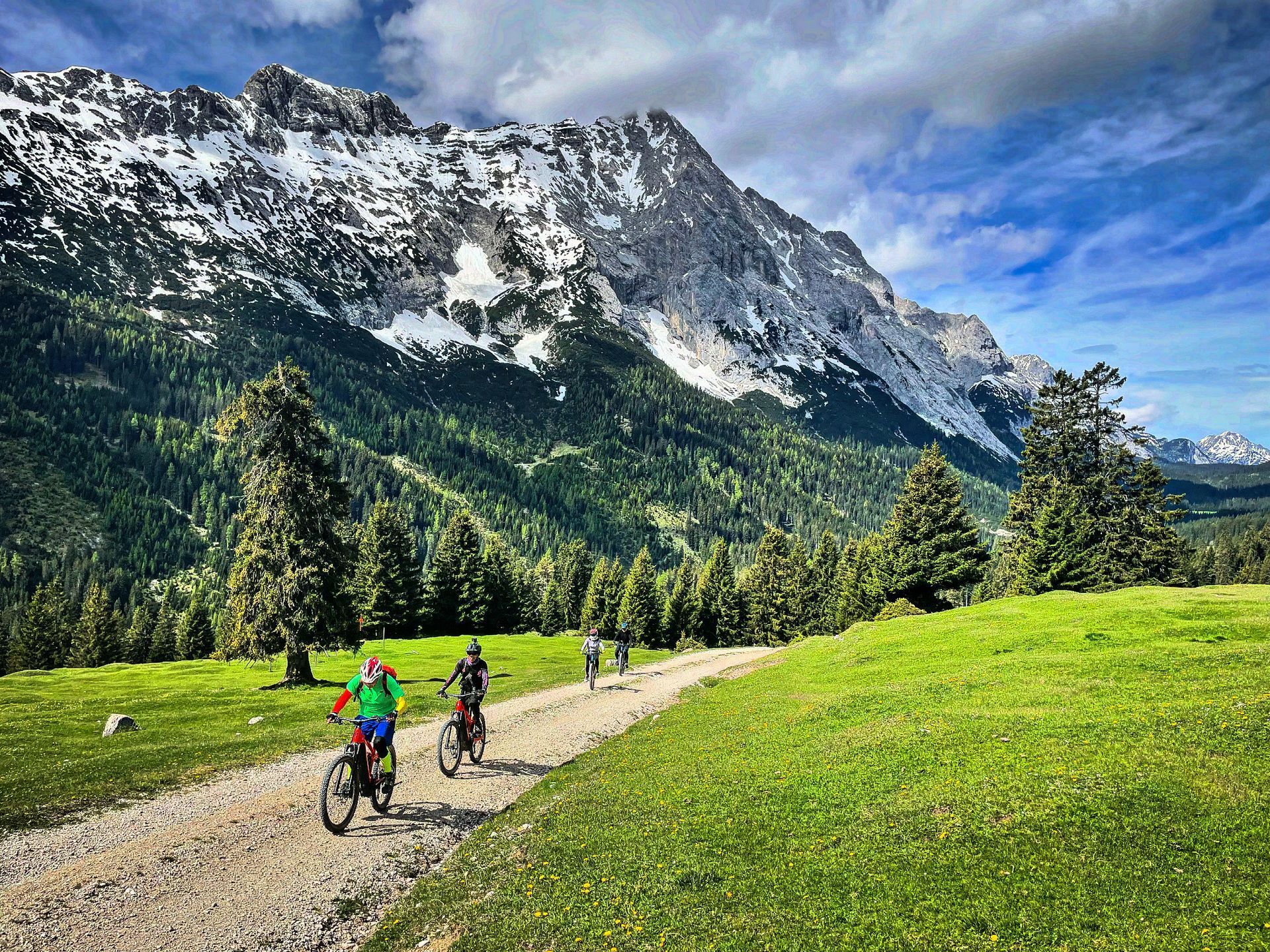 A group of people are riding bikes down a dirt road in the mountains.