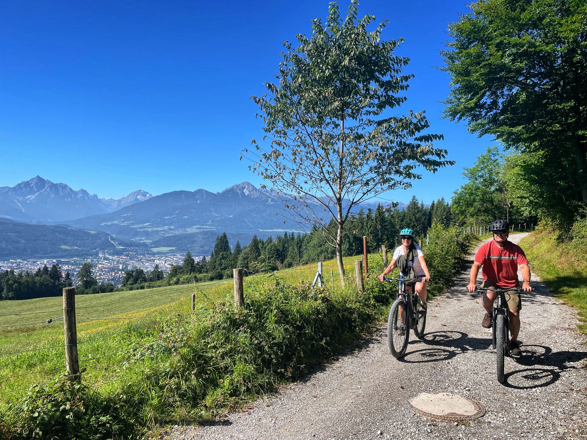 A man and a woman are riding bicycles down a dirt road.