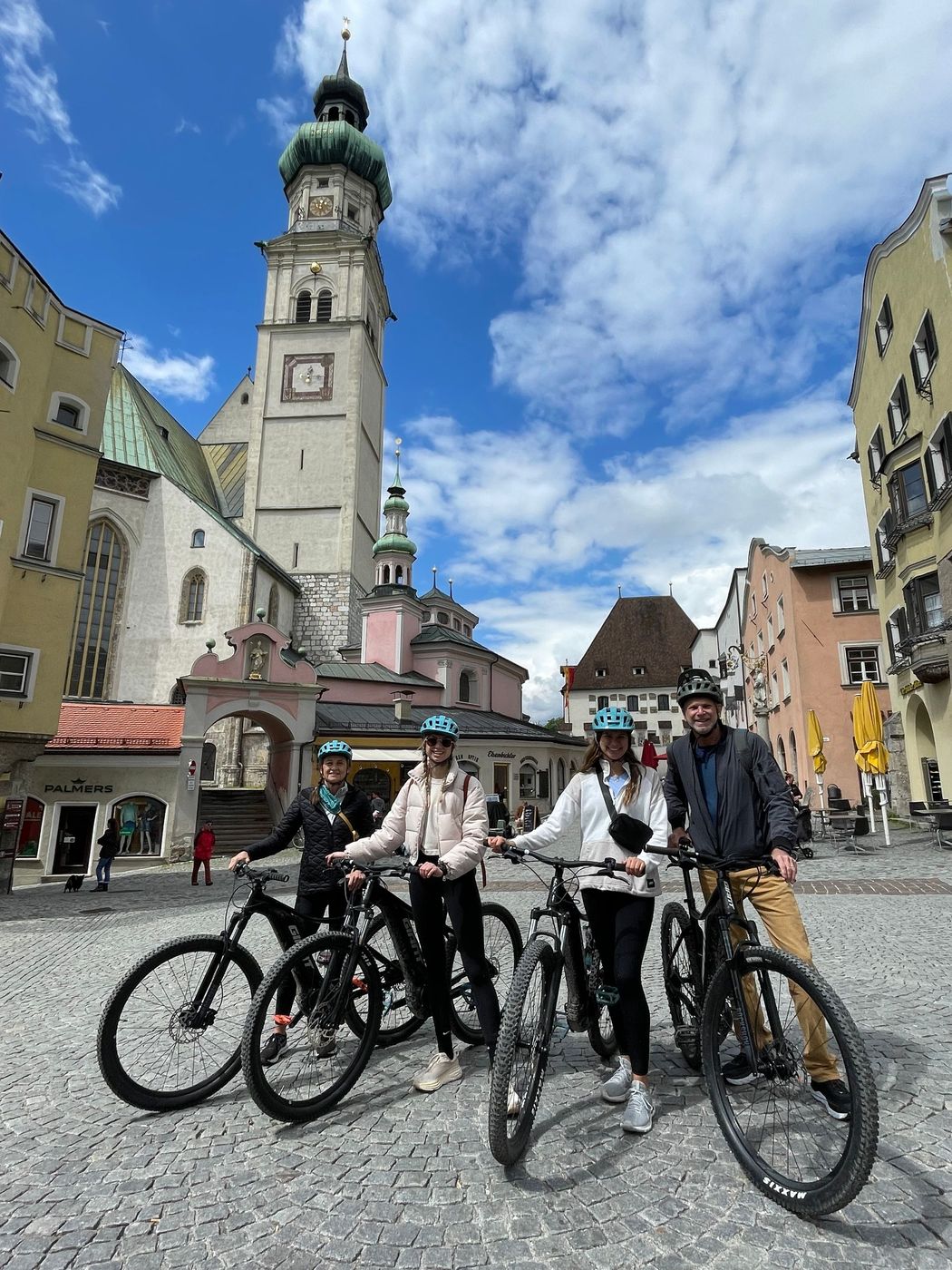 A group of people are standing next to each other on bicycles in front of a clock tower.