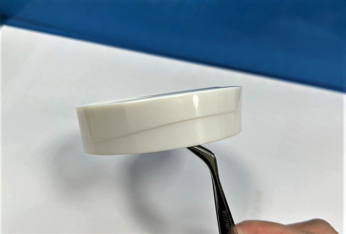 A person is holding a piece of white tape with tweezers.