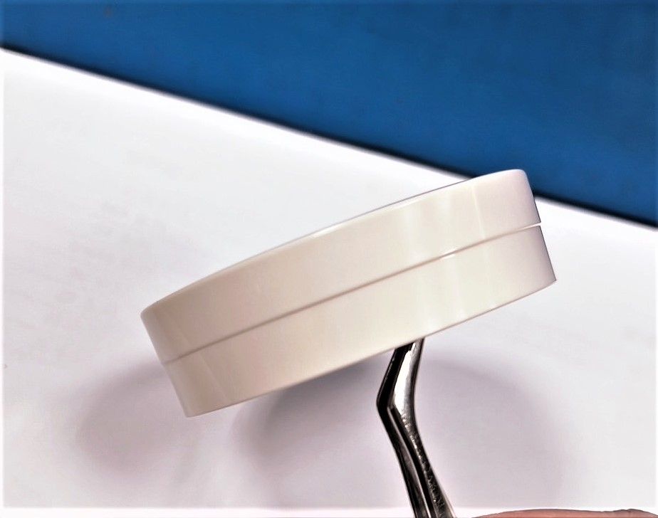 A person is holding a pair of tweezers over a white object