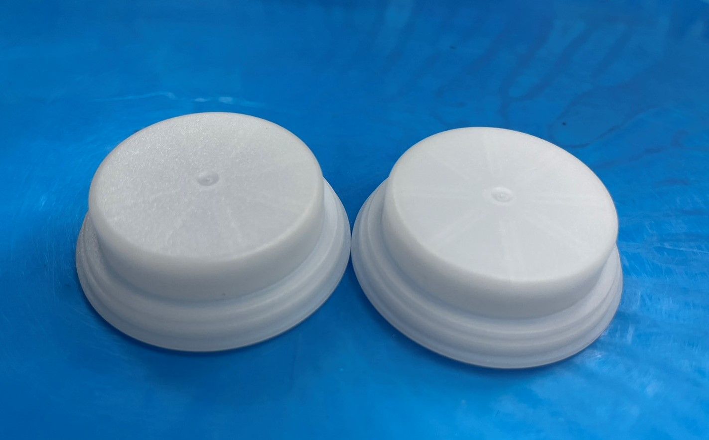 Two white plastic lids are sitting on a blue surface.