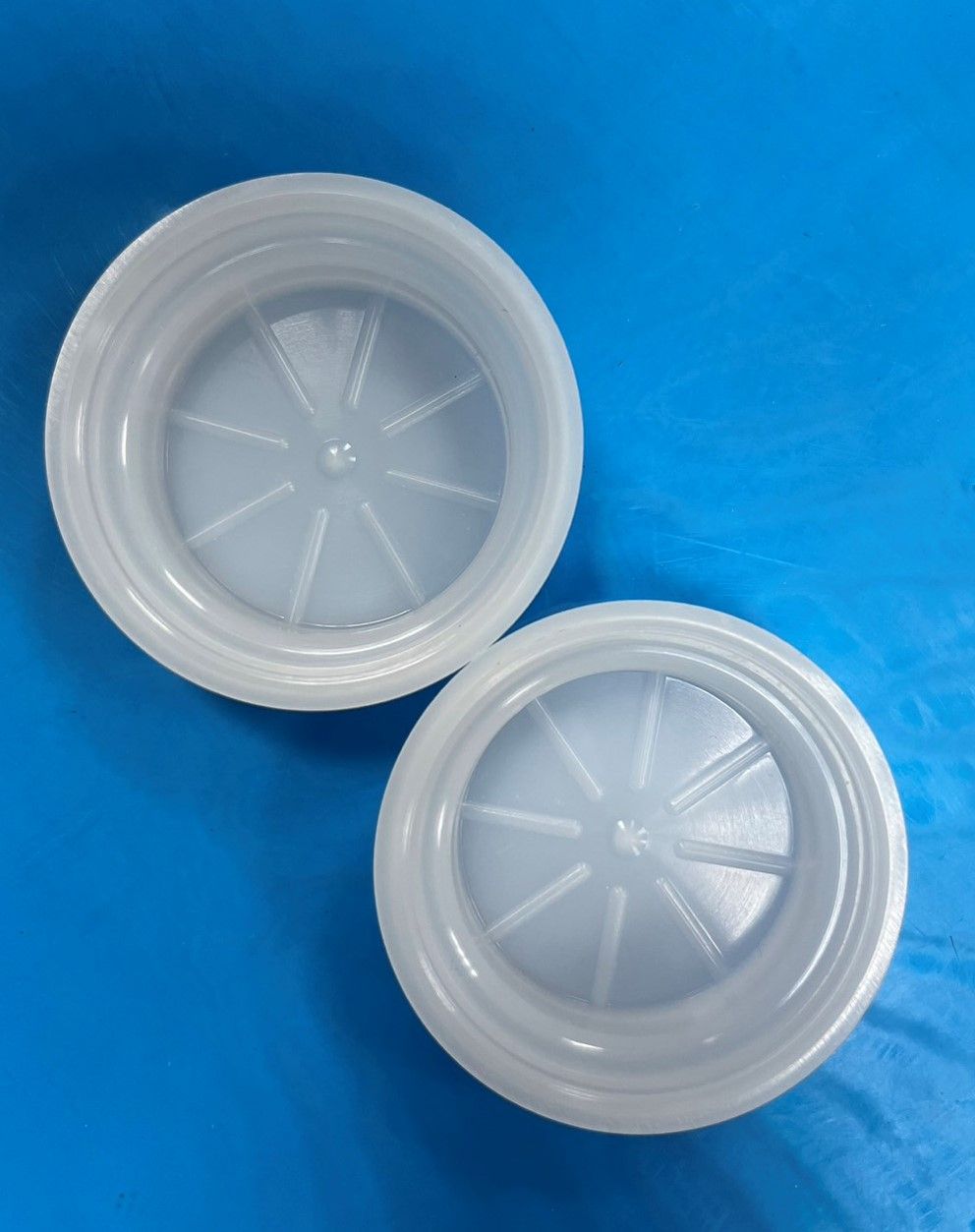 Two white plastic lids on a blue surface