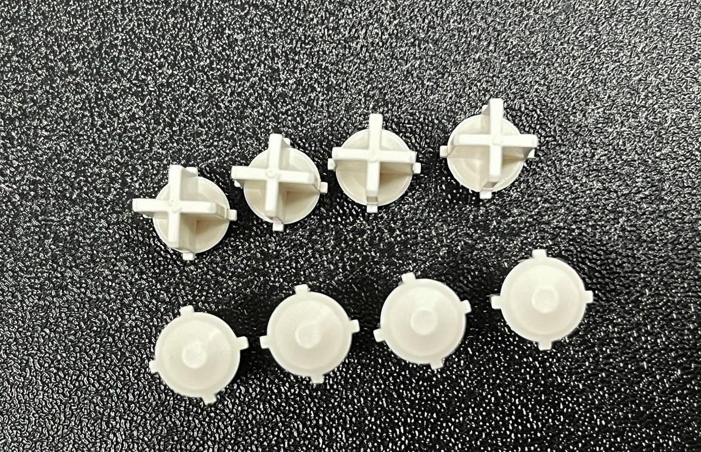 A group of white plastic buttons with crosses on them are sitting on a black surface.